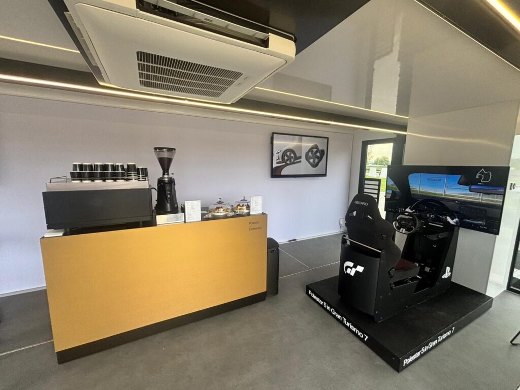 Polestar 2 Polestar brand activation space with Tom’s Coffee gold branded coffee bar alongside the Polestar 5 Gran Turismo 7 racing simulator
