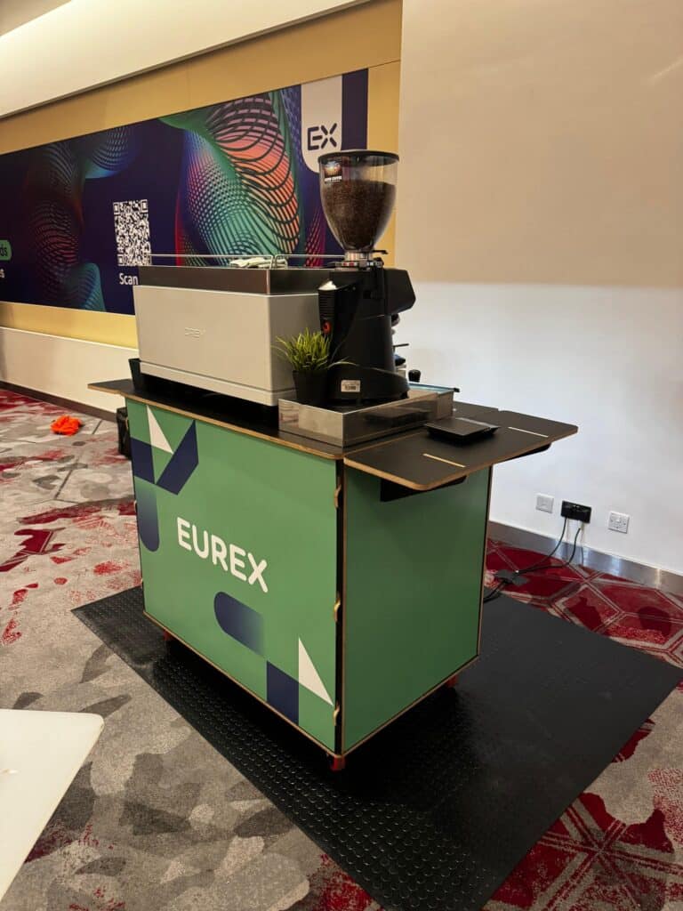 Green Eurex branded coffee bar by Tom’s Coffee with espresso machine and grinder at FIA IDX 2026, Park Plaza Westminster Bridge