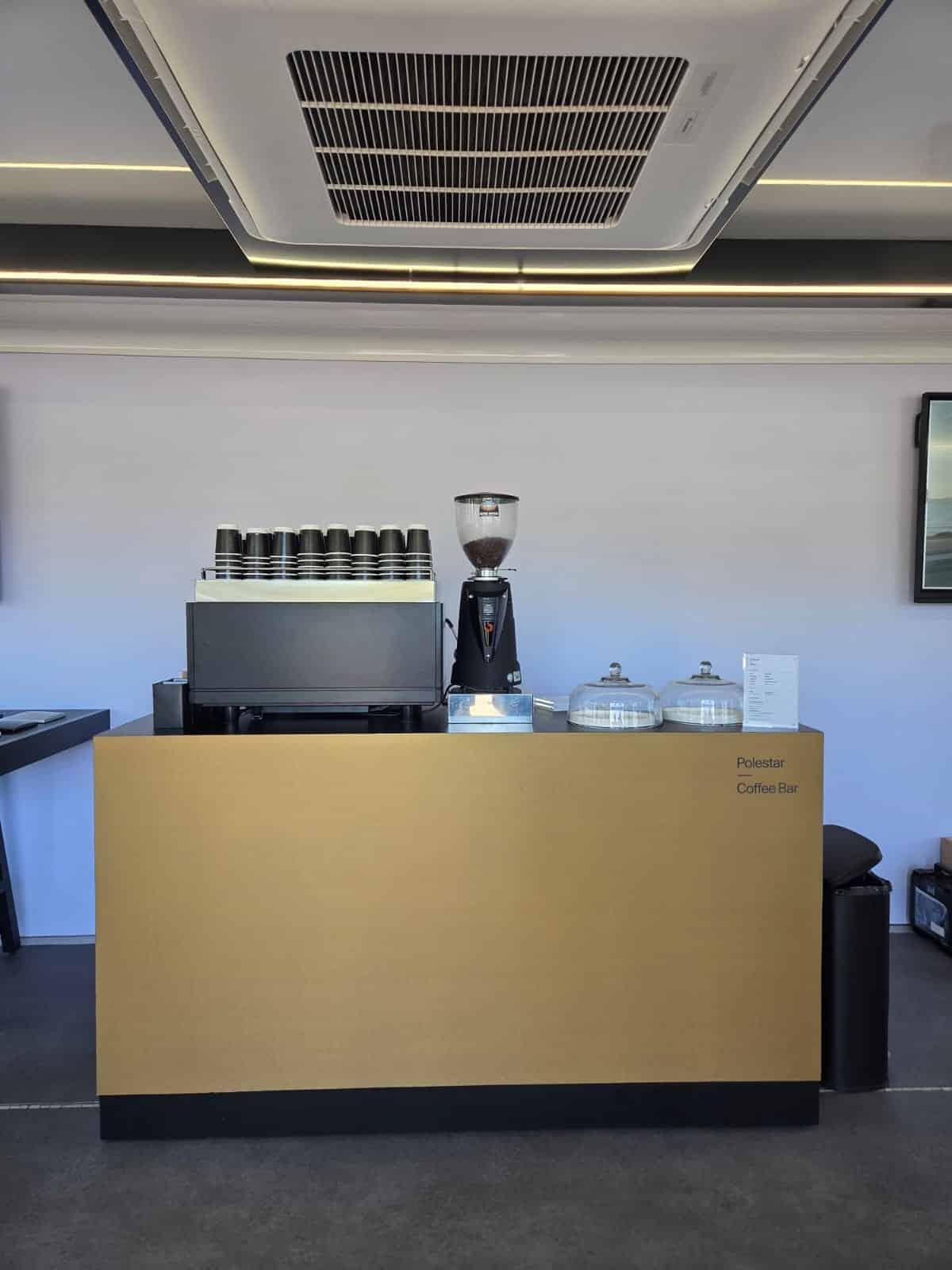 polestar 1 Gold Polestar-branded coffee bar by Tom’s Coffee with espresso machine, grinder and stacked cups at a Polestar brand activation